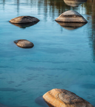 This image of Lake Tahoe portrays a tranquil scene with rocks emerging from the water. The arrangement of the rocks creates a peaceful, natural progression through the image, adding to the calm and soothing atmosphere.