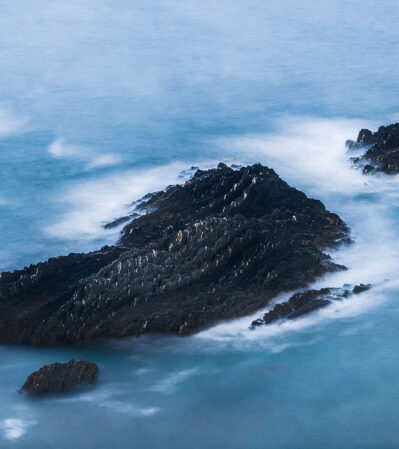 The rocky shoreline at Arrifana, in the south of Portugal, is an inspiration for artists. This rugged black rock formation emerging from the pale blue ocean, could pass as a dinosaur. The water surrounding the rocks is smooth and ethereal, in contrast with the sharp and jagged texture of the rocks.
